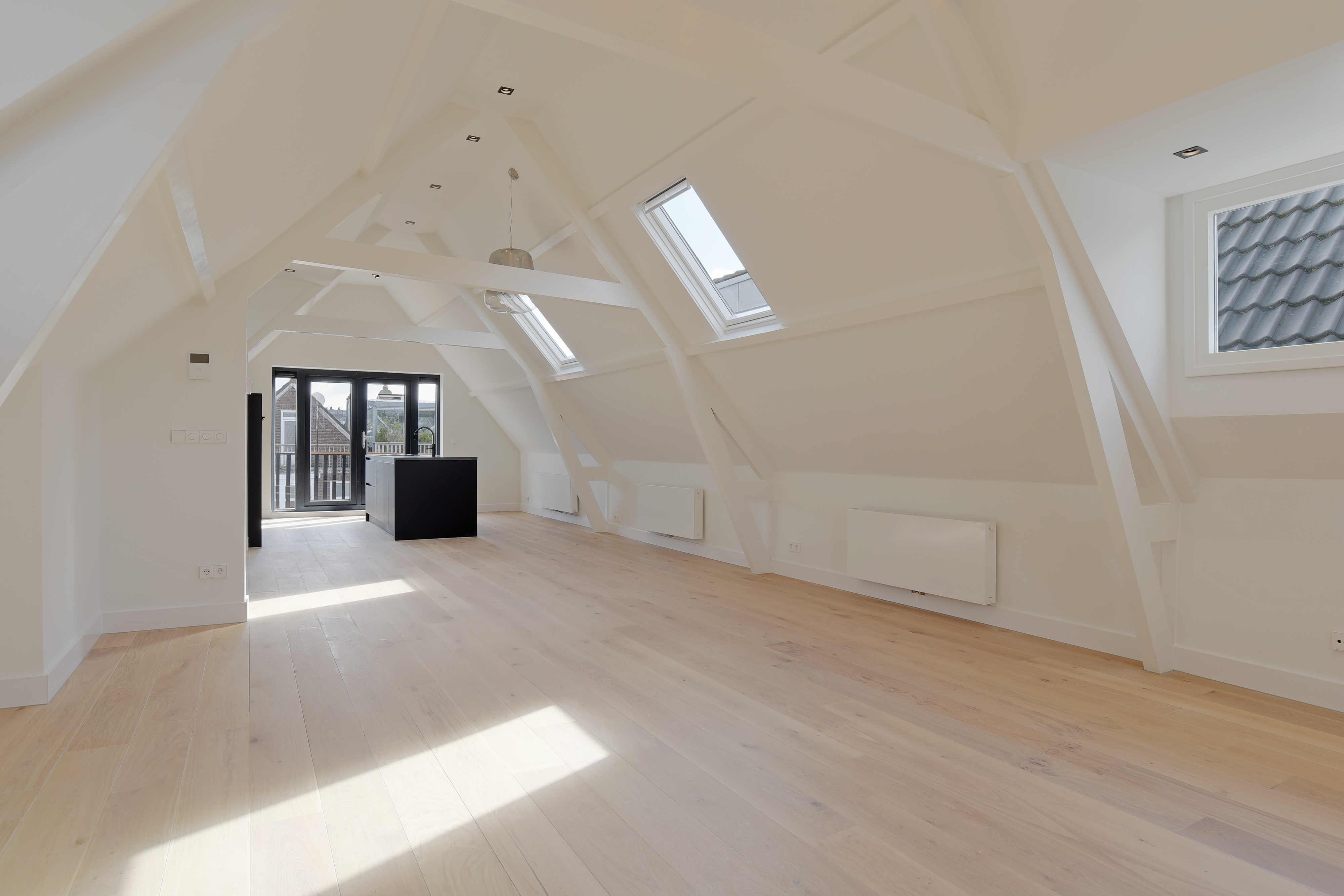 Lichte woonkeuken met zwart kookeiland onder de kap in Penthouse Amsterdam