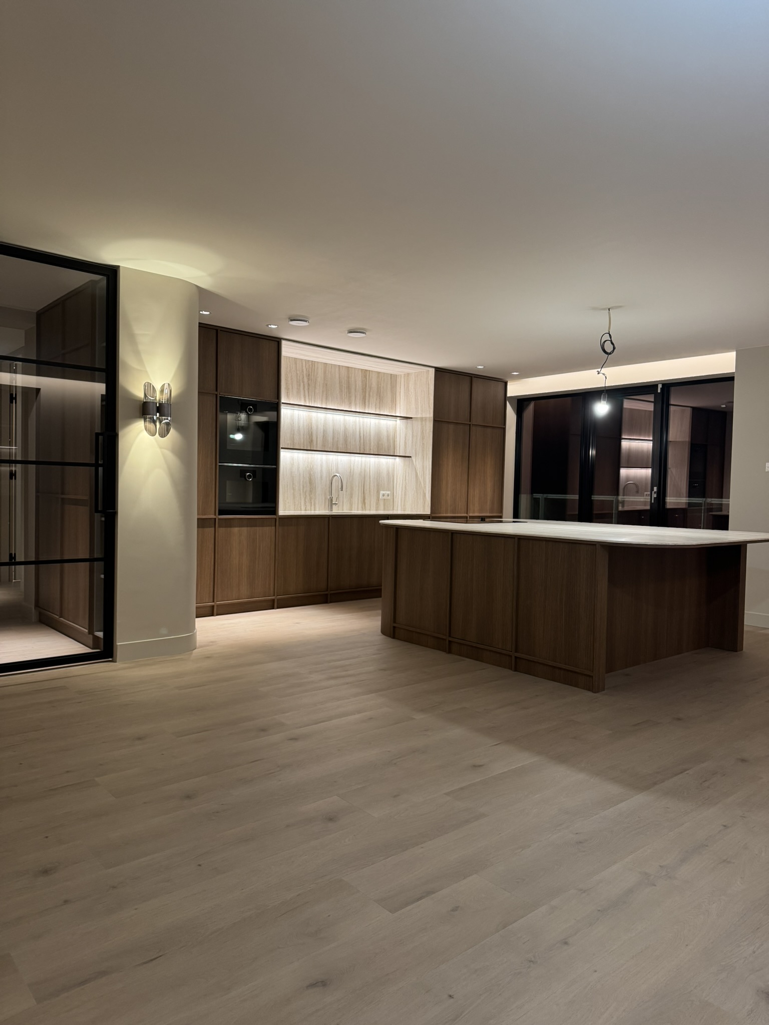 Maatwerkkeuken in notenhout met travertin werkblad en indirecte verlichting, gerealiseerd door RAW-Building