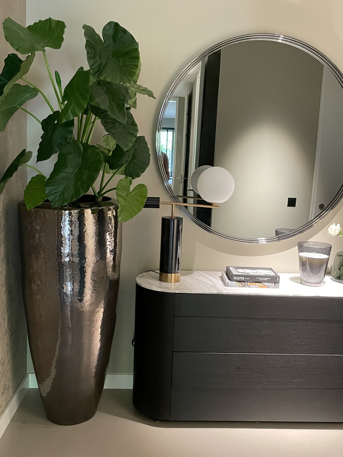 Dressoir met ronde spiegel en lamp in een gestyled appartement