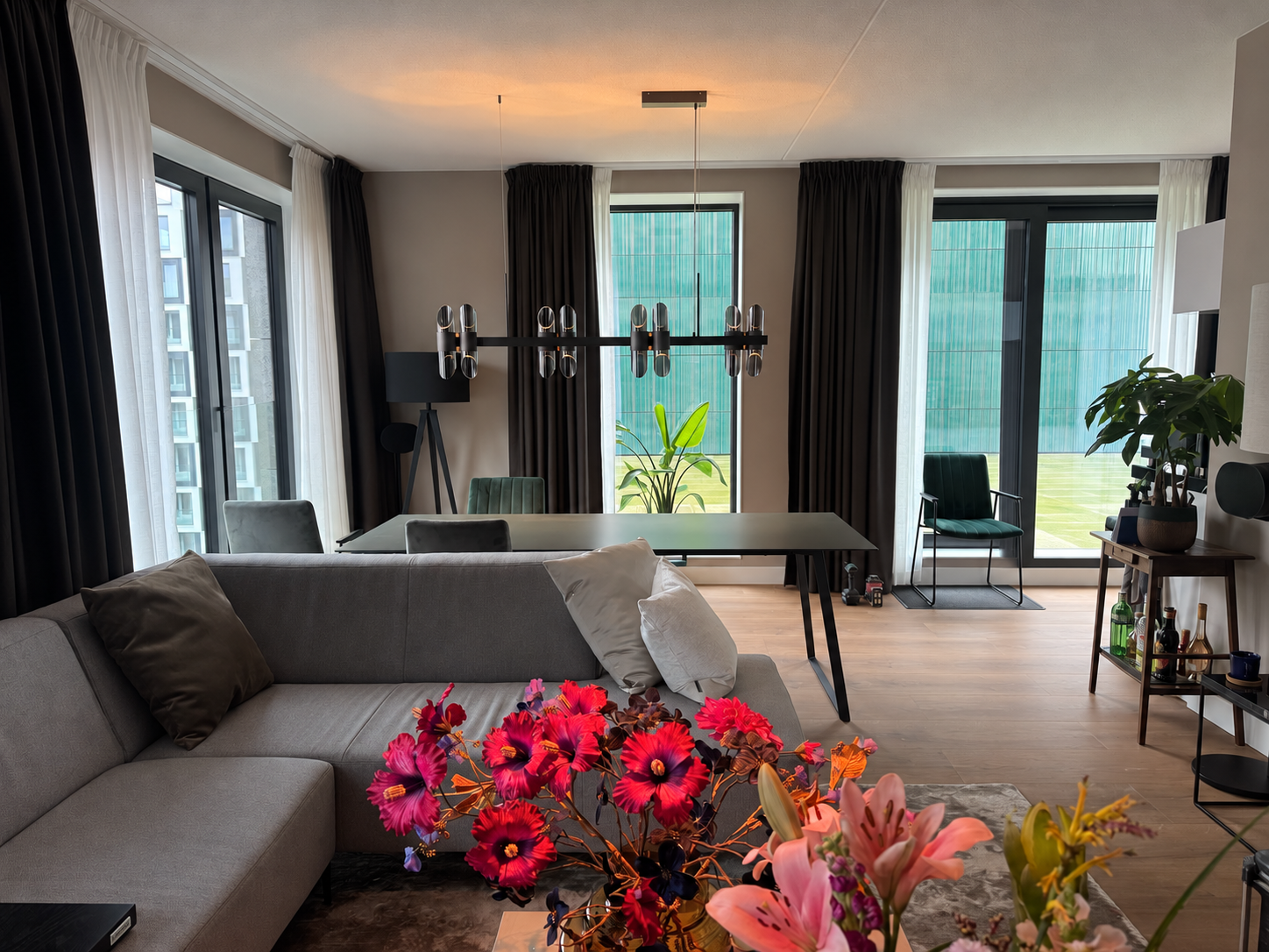 Woonkamer met grijze hoekbank, bloemen en eettafel in Hyde Park
