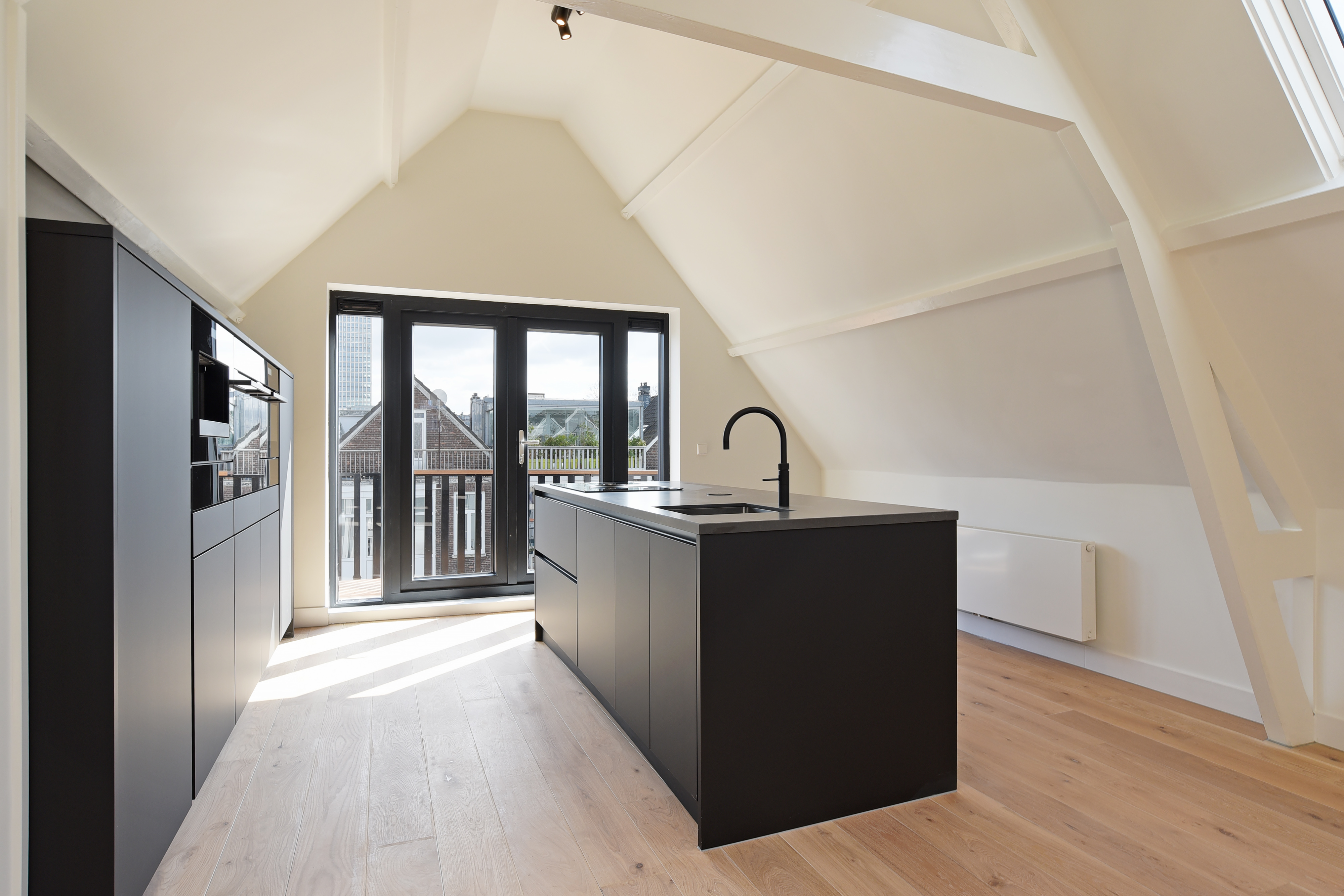 Keuken met zwart eiland en doorkijk naar de kapconstructie