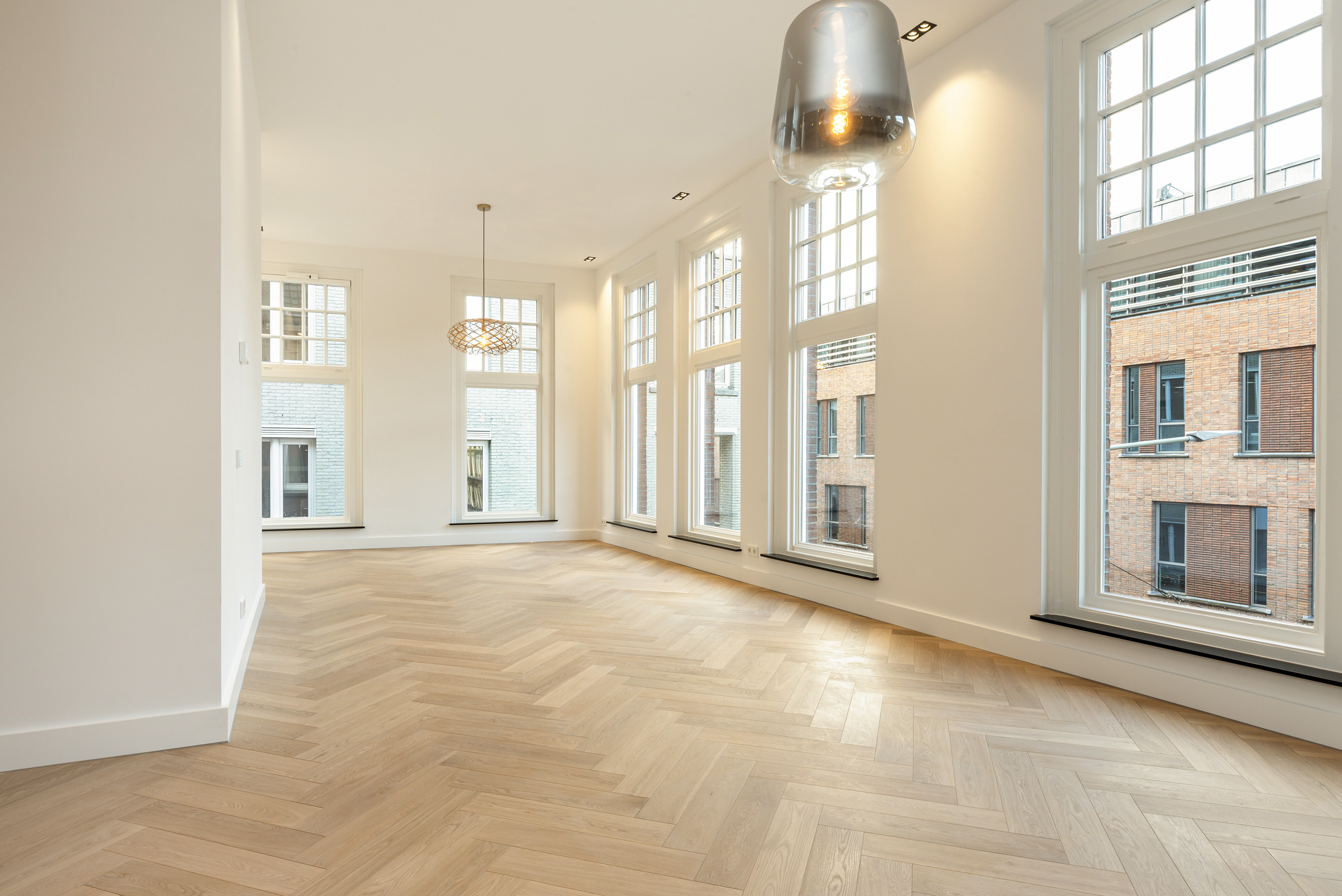 Woonkamer met vishgraatvloer en doorkijk naar de keuken